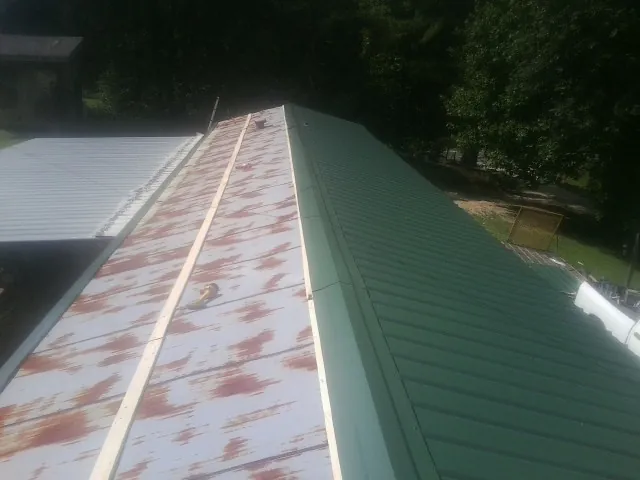 Old rusted panels beside newly installed green metal roofing — Wind Damage Roof Repair by Roofing Brothers in Jacksonville Beach