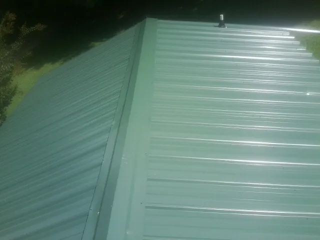 New green metal panels meeting at the ridge of a roof — Flat Roof Repair work by our crew in Jacksonville Beach