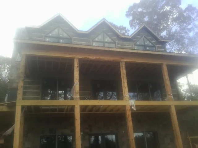 Dormers and porch framing on a large log home under construction — Roof Coating work by our crew in Jacksonville Beach
