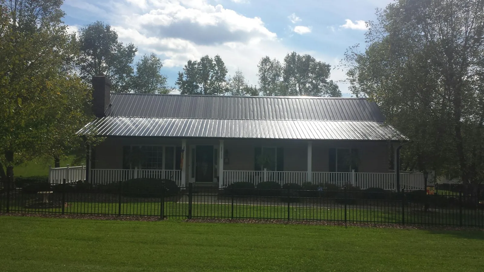 Gray metal roof on a brick ranch with a full width front porch — Gutter Guard Installation work by our crew in Jacksonville Beach