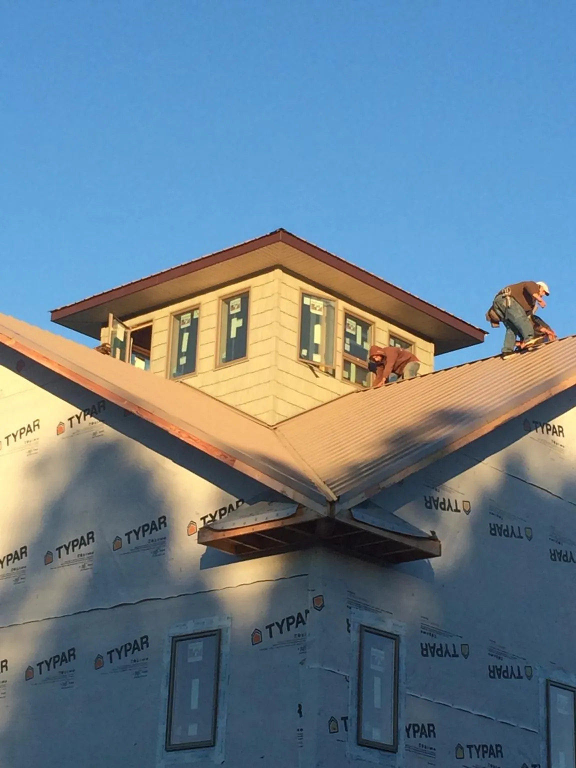 Roofers working around a rooftop cupola on a new metal roof at sunset — Roof Waterproofing in Jacksonville Beach by Roofing Brothers